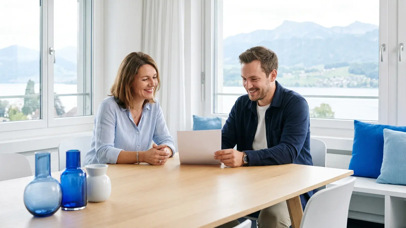 Beraterin und Gründer gehen an einem hellen Besprechungstisch mit Blick auf den Zürichsee eine Liste durch
